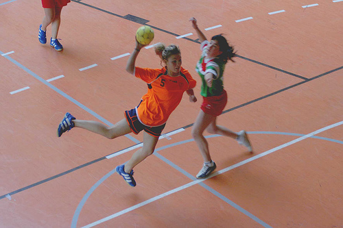 Auf dem Bild sind zwei Handballspielerinnen. Eine Spielerin wirft gerade den Ball.
