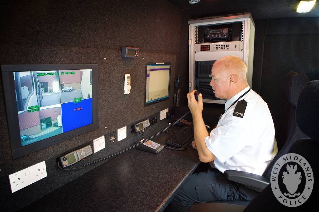 Auf dem Bild ist ein Polizist vor Computer-Bildschirmen zu sehen