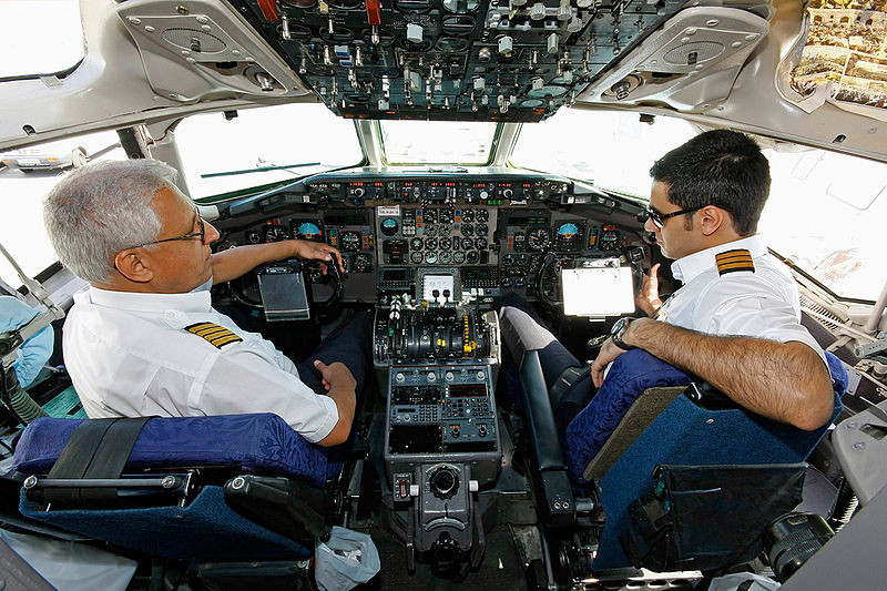 Auf dem Bild ist ein Pilot und ein Copilot in einem Flugzeug zu sehen, der Co·pilot sitzt rechts
