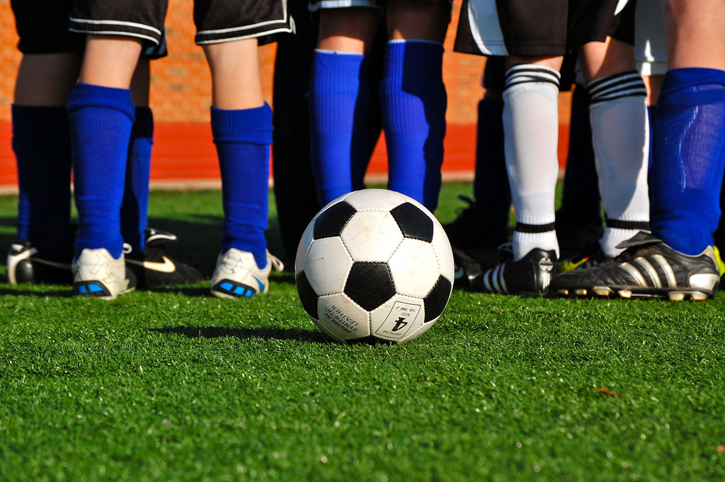 Auf dem Bild ist ein Fuß-ball zu sehen und Beine von Fußball-spieler