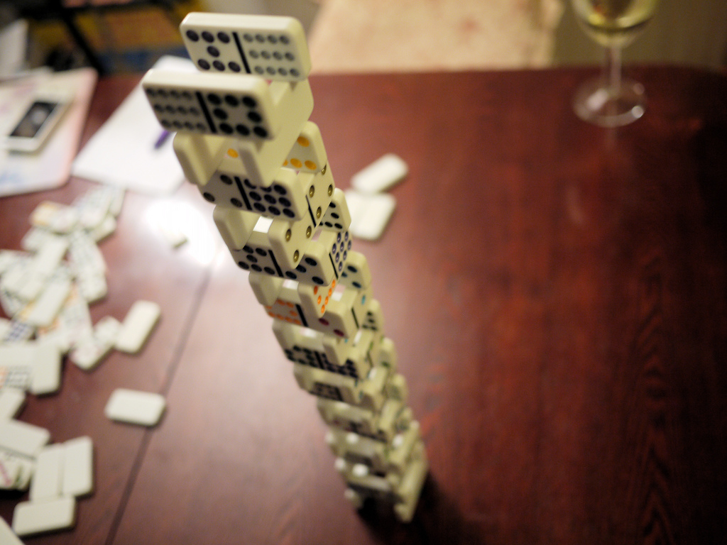Auf dem Bild ist ein Kartenhaus aus Domino-steinen zu sehen