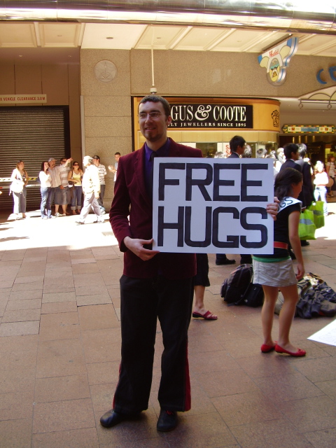 Auf dem Bild ist Juan Mann mit einem Free Hugs Schild zu sehen