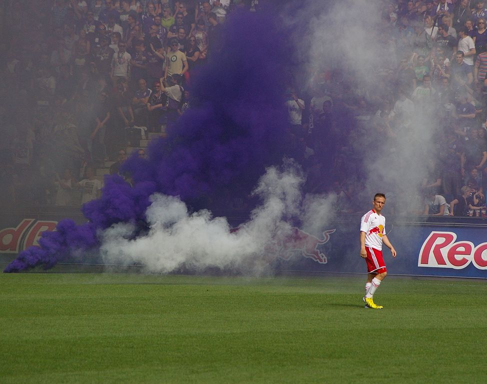 Auf dem Bild ist Rauch von einer Rauchgranate zu sehen. In einem Fußball-stadion