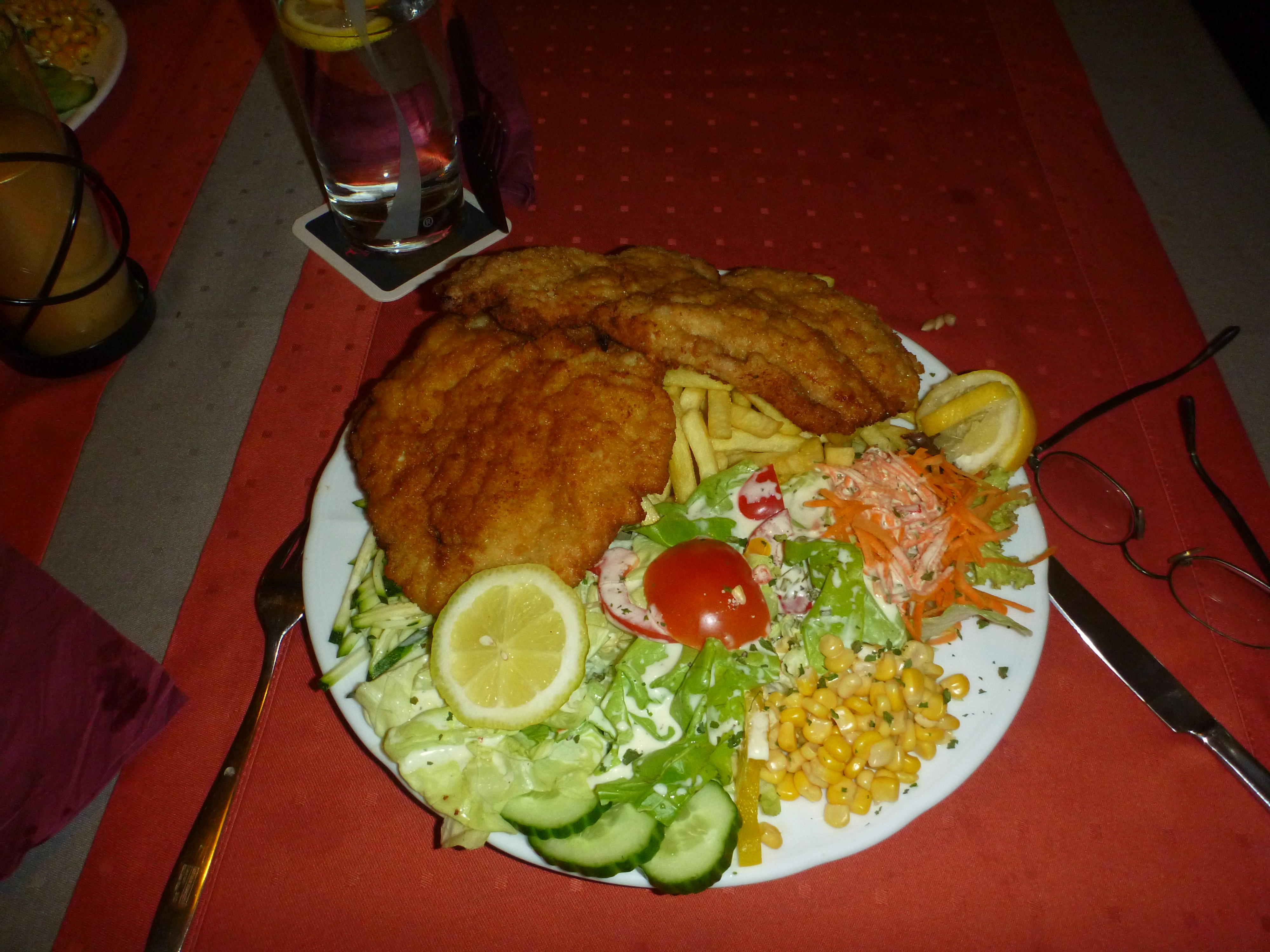 Auf dem Bild ist ein Teller mit Schnitzel, Pommes und Salat zu sehen