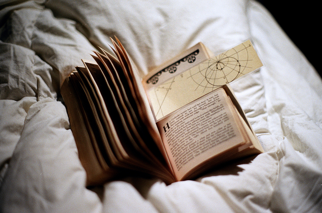 Auf dem Bild ist ein Buch mit Lesezeichen auf einer Decke zu sehen